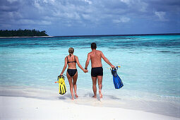 Young couple with flippers in the water, Four Seasons Resort, Kuda Hurra, Maledives, Indian Ocean