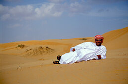 Man lying in the sand at the desert, Sultanat Oman, Middle East, Asia