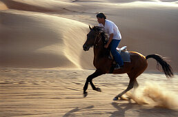 Junger Mann reitet ein Pferd in der Wüste, Sultanat Oman, Vorderasien, Asien