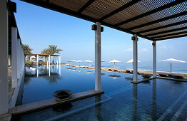 Sonnenschirme spiegeln sich im Pool, The Chedi Hotel, Maskat, Oman