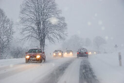 Autos im Schneetreiben auf Landstrasse, Bayern, Deutschland