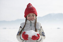 Mädchen 5-6 Jahre, hält Schnee in den Händen