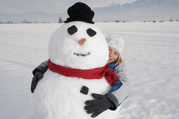 Junge umarmt einen Schneemann