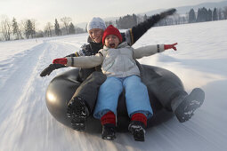 Mädchen und Junge lassen sich mit Autoreifen ziehen Snowtubing