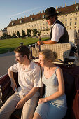 Fiaker coachman showing tourists Neue Hofburg during a city tour, Vienna, Austria