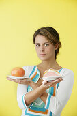 Frau hält zwei Teller in ihren Händen mit Grapefruit und Kuchen