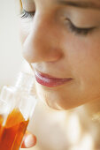 Young woman smelling a bottle of perfumed body oil