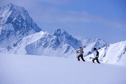 Two skier walking through snow, mountains in the background, Kuehtai, Tyrol, Austria