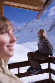 Zwei junge Frauen sonnen sich auf der Terrasse einer Skihütte, Kühtai, Tirol, Österreich