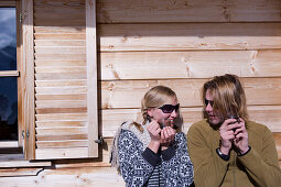 Couple sunbathing on terrace of ski lodge, drinking tea, Kuehtai, Tyrol, Austria