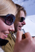 Couple sunbathing on terrace of ski lodge, drinking tea, Kuehtai, Tyrol, Austria