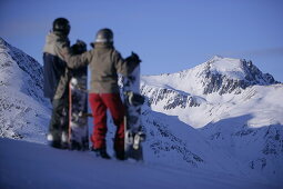 Young couple standing with snowboards, enjoying mountain view, Kuehtai, Tyrol, Austria