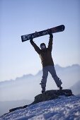 Person hebt Snowboard in die Höhe, Kühtai, Tirol, Österreich