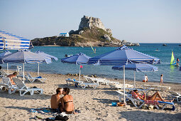 Couple at Kefalos beach kissing, Kastri island with capel St. Nicholas in background, Kefalos, Kos, Greece