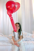Mädchen spielt mit roten Luftballons