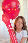 Girl holding red balloons, portrait