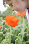 Young girl looking down at poppy