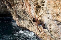 Mann klettert auf einem Felswand bei Puerto Christo, Mallorca, Spanien
