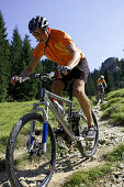 Two mountainbikers downhill on path with broken stones, Bavaria, Germany