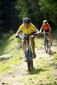 Mountainbiker downhill auf Schotterweg, Oberammergau, Deutschland