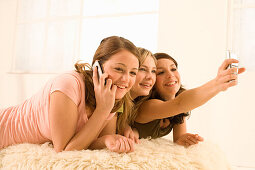 Teenage girls (14-16) on bed using mobil phones