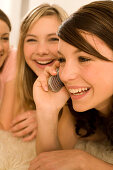 Three teenage girls (14-16), one using mobile phone