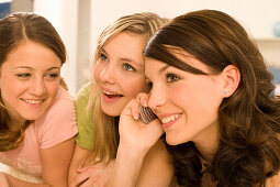 Three teenage girls (14-16), one using mobile phone