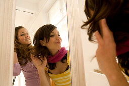 Two teenage girls (14-16) looking into mirror