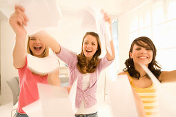 Weibliche Teenager (14-16) schmeißen Blätter durchs Zimmer