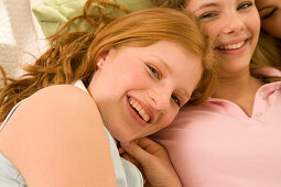 Two teenage girls (14-16) snuggling together on bed, close-up