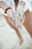 Frau lässt Sand aus den Händen rieseln, close up