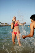 Young couple splashing each other in sea