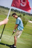 Male golfer preparing to hit ball, Apulia, Italy