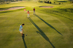 Golfers on golf course, long shadows, Apulia, Italy