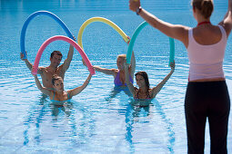 Trainer showing young people stretching exercises in pool, Apulia, Italy