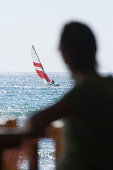 Unrecognizable person on beach, looking at sailboat on sea, Apulia, Italy