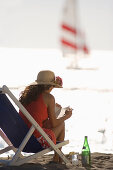 Junge Frau liest im Liegestuhl am Strand, Apulien, Italien