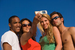 Four young people taking picture with camera phone, Apulia, Italy