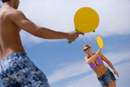 Young couple playing paddle ball on beach, Apulia, Italy