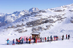 Skifahrer stehen in der Schlange am Skilift an einem sonnigen Wintertag, Marmolada, Dolomiten, Italien