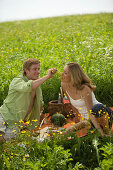 Junges Paar beim picknicken, Mann füttert Frau mit Weintrauben