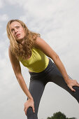 Woman resting while jogging, hands on knees