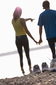 Couple standing (after jogging) on lakeshore, feet in water