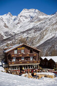 View to the Hotel and Restaurant Hohnegg in front of a snowy mountain, Saas-Fee, Valais, Switzerland