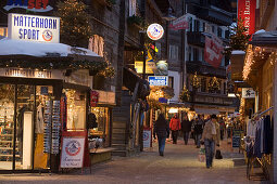 People walking over the illuminated shopping street Bahnhofstrasse in the evening, Zermatt, Valais, Switzerland