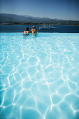 Couple enjoying the view from a pool overlooking the bay of Porto Vecchio, Southern  Corse, France