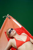 Young woman sunbathing on boat, wearing red bikini, Starnberger See, Upper Bavaria, Germany