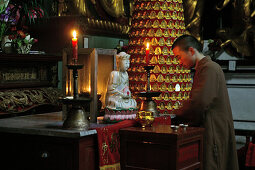 Ein Mönch kniet vor weissem Jade Buddha, Sangchan Kloster, Jiuhuashan, Provinz Anhui, China, Asien
