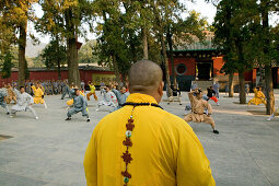 Shaolin Buddhist monk watching Kung Fu students, Shaolin Monastery known for Shaolin boxing, Taoist Buddhist, Song Shan, Henan province, China