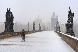 Mann fährt Fahrrad über Karlsbrücke, Prag, Tschechien